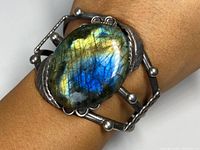 Large American Indigenous Old Pawn sterling silver cuff bracelet worn on wrist, showcasing the large oval labradorite stone with iridescent blue, green, and gold colors.