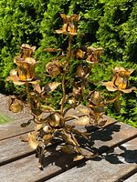 Full view of the gilt floral candelabra on wooden table outdoors