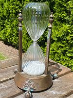 Full front view of sand timer with bronze frame and glass hourglass
