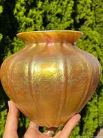 Oblique frontal view showing the vase's lobed, ribbed body with a warm golden, iridescent finish.
