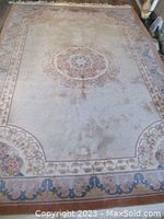 Full view of rectangular Persian-style area rug laid flat to show carved floral medallion and surrounding border design.