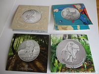 Four presentation folders each containing a .9999 fine silver $20 coin displayed on white surface