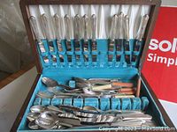 Open wood chest showing top tier slots filled with forks and knives, turquoise felt lining