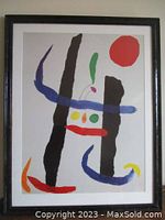 Frontal photo of the Joan Miro photo-lithograph in dark wood frame with colorful abstract shapes and red circular shape in top right corner