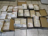 Overhead view of 19 shoe boxes filled with first day covers arranged on a tiled floor
