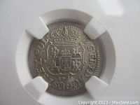 Close-up of obverse side of silver coin showing crowned coat of arms and surrounding Latin text.