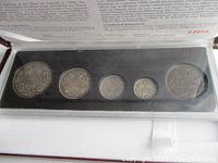 Five coins displayed side by side in foam-lined case