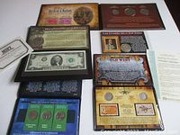 Overview of folders containing coins and stamps, including Bicentennial dollars, 1963 half dollar, historical stamps, and certifications