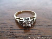 Front view showing center diamond in white gold mount and heart-shaped side diamond accents