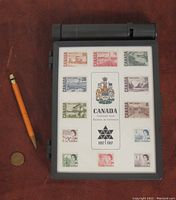 Full view of the original 1967 Canada Centennial 12-piece stamp set sealed in the original plastic storage case with integrated water reservoir and roller at the top.