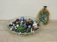 Wide view of vintage marbles in clear dish showing variety of colors and patterns, including cats eyes, salt and peppers, clearies, minis, and milkies.
