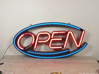 Front view of the illuminated LED OPEN sign showing red and blue neon-style lighting in an oval shape.