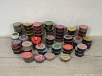 View of 44 stacked round metal tins of Dylon Cold fabric dye in various colors.
