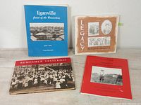 Four history books arranged sitting on a white surface: Eganville Jewel of the Bonnechere, Legacy Portraits of a Community, Remember Yesterday, and Pioneers Canada's First Polish Settlement.