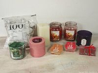 Overview of all items in the lot including various scented jar candles, pillar candles, wax melts, and bag of tea light candles