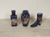 Group photo of three cobalt blue mini vases showing their shapes and painted decorations.