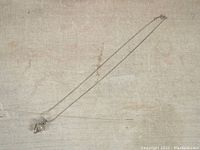 Full view of the silver-tone necklace with caged pearl pendant laid flat showing overall length and pendant position.