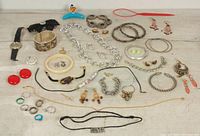 Photo showing entire lot of vintage costume jewelry including bracelets, necklaces, rings, earrings, and a wristwatch arranged on a neutral background
