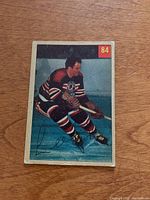 Front of 1954-55 Parkhurst Lee Fogolin hockey card, numbered 84, showing player in Chicago Black Hawks uniform with slight corner wear and small creases.