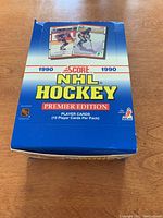Front view of unopened blue box of 1990 Score NHL Hockey Premier Edition hockey cards featuring images of player cards with NHL branding.