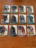 Full view of all 12 hockey cards arranged on wooden surface showing different players including duplicate cards of Brett Hull.