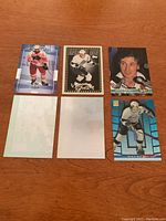 Top view of all six Wayne Gretzky hockey cards arranged in two rows on a wooden surface showing front and backs of cards