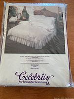 Front packaging image showing a bedroom setup with a white bed sheet set on a bed, branding and care instructions visible.