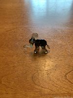 Small glass elephant figurine photographed from the side on a wooden surface.