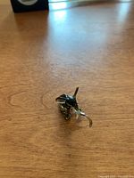 Photo showing the glass elephant figurine on wooden surface from a front angle highlighting its shape and clear glass tusks and trunk.