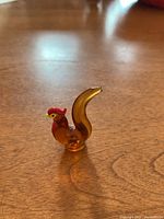 Glass rooster figurine side view showing amber colored glass body and red comb