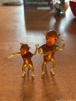 Image showing two amber-colored glass monkey figurines on a wooden surface