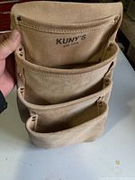 Close-up front view of the Kuny's leather tool pouch showing three pockets and branding.