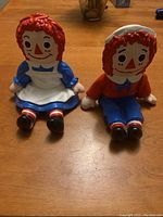 Front view of Raggedy Ann and Andy bookends showing colorful detailed figures sitting with hands on knees.