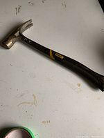 Full view of the Stanley claw hammer showing the black fiberglass handle with yellow accents and brand sticker.