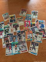 33 vintage hockey cards laid out on wood surface showing different players, teams, and card designs with visible signs of wear