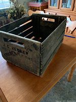 Side view of vintage wooden crate with stencil markings and slatted bottom showing its rustic wear and construction