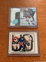 Front view of two Wayne Gretzky hockey cards in protective sleeves showing gameplay and MVP style designs.