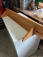 Wooden pine shelf mounted on a white surface showing the entire length and back panel.