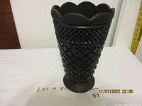Full view of black glass vase showing scalloped rim and textured body pattern.