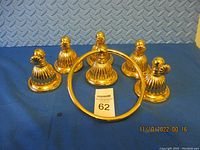 Full set of six gold-tone bathroom accessories laid on blue fabric background, one towel ring and five hooks.