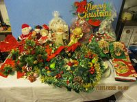 Full view of the Christmas decorations including artificial wreaths decorated with pinecones, tinsel, Santa and angel figurines, and a Merry Christmas sign.