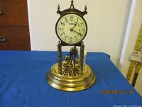 Photo of the Forestville anniversary clock without glass dome showing dial, brass base, decorative columns, and broken pendulum wire.