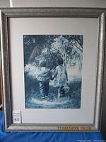 Framed print showing monochrome image of little boy and girl walking hand in hand on a wooded path, surrounded by trees, taken from the front.