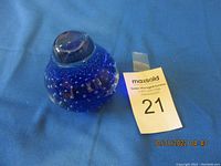 Full view of the blue glass paperweight with a rounded dome shape and bubble inclusions.