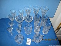 Full set of pinwheel crystal glasses of different sizes displayed on blue cloth, 22 pieces total, one with chip