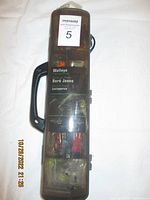 Front view of black R2F tackle box showing handle and transparent cover with visible fishing lures inside.