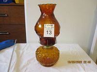 Front view of vintage amber glass oil lamp with red glass chimney and embossed base.