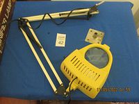 Full view of the vintage magnifier lamp, showing the flexible arm, yellow lamp head with magnifying glass, and clamp base.