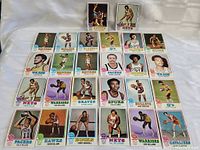Photo showing 31 different 1973-74 Topps basketball cards laid out in 5 rows, featuring players from various teams like Bullets, Spurs, Warriors, Bucks, Nets, Hawks, Cavaliers, Packers, and Squires.