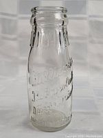 Close-up of the clear glass bottle showing embossed script lettering for chocolate milk and company name.